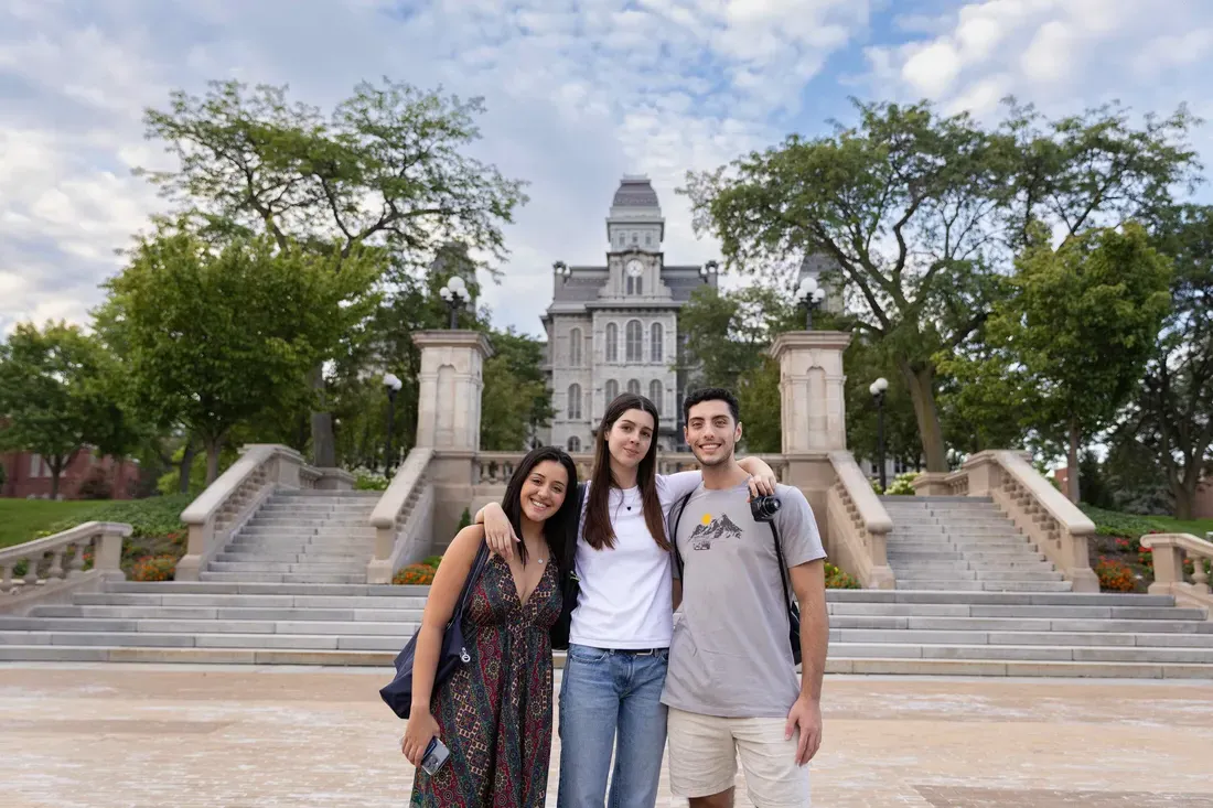 Three international students standing outside smiling.